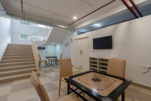 a living room with a table and a tv and stairs at Better Life Homes - For active seniors above 50 years in Barog