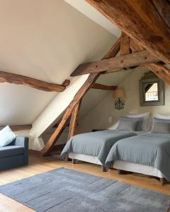 un dormitorio en el ático con 2 camas y un sofá azul en Maison avec piscine & tennis partagés - proche Châteaux de la Loire - 1h30 de Paris, en Combreux
