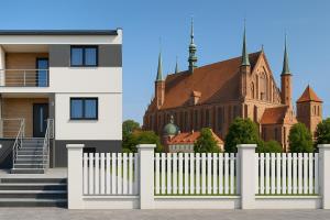 Una valla blanca delante de un edificio con una iglesia. en Bezpieczna Przystań, en Frombork