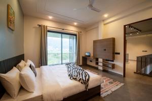 a bedroom with a bed and a large window at SaffronStays Pebble House - 3BR riverside villa with glass walls, terraces & Nun River views, Dehradun in Dehradun