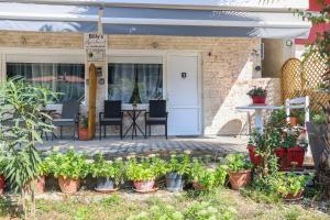 a patio with a table and chairs and potted plants at Billy's Luxury Suites - 2 by Booking Kottas - Kriopigi in Kriopigi