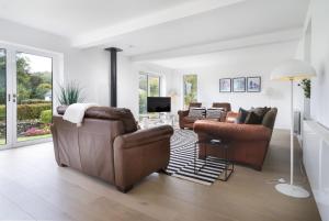 a living room with leather furniture and a tv at Fellbeck Holiday Home - Cartmel in the Lake District in Cartmel