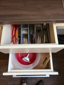 a drawer in a cabinet with a red bowl and utensils at Szántó Prime Residence in Szolnok