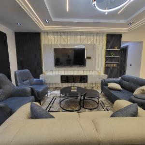 a living room with couches and a flat screen tv at Grabbo Luxury Apartments in Gwarinpa