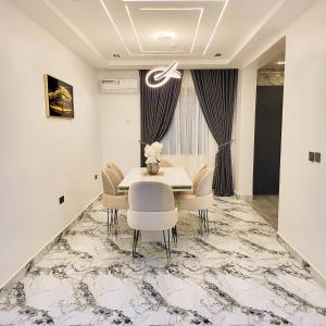 a dining room with a white table and chairs at Grabbo Luxury Apartments in Gwarinpa