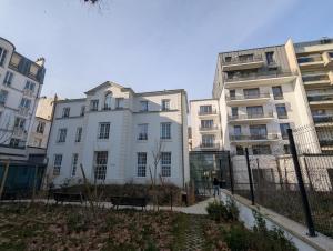un grupo de edificios con una persona caminando delante. en Zenao Appart'hôtels Saint-Mandé, en Saint-Mandé
