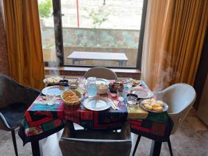 a table with food on it with chairs and a window at Old District View Hotel kazbegi in Kazbegi