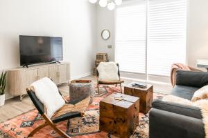 a living room with a couch and chairs and a tv at The Chattanooga Crossroads Condo in Chattanooga