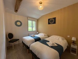 a bedroom with two beds and a chair and a window at Le Verger - Gite 8 personnes en campagne et rivière By Primo in La Forêt-sur-Sèvre