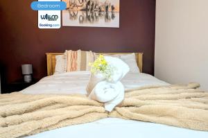 ein Bett mit einem Handtuch und einem Blumenstrauß in der Unterkunft 5BR House By WillCo Property Short Lets & Serviced Accommodation Derby With Games, Parking Perfect For Contractors in Derby