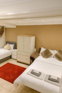 une chambre avec deux lits et une armoire et un tapis rouge dans l'établissement Stunning home next to Excel, London City Airport and East London University, à North Woolwich