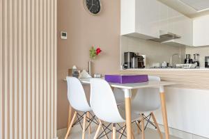 - une cuisine avec une table blanche et des chaises blanches dans l'établissement Silkhaus Chic 2BDR in Radiant Boulevard, à Mushayrib