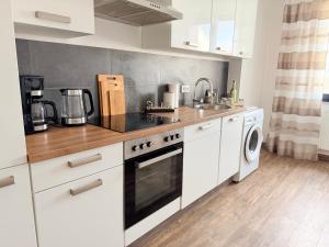 een keuken met witte kasten en een kookplaat oven bij BIELEFELD CITY APARTMENTS - Cozy in Bielefeld +17 foto's
