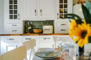 a kitchen with white cabinets and a table with a sunflower at Beautiful Cottage in Haworth by 53 Degrees Property, Amazing Location, The Perfect Retreat! in Haworth +28 photos