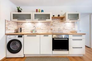 a kitchen with white cabinets and a washer and dryer at The Cozy Corner - Passau in Passau