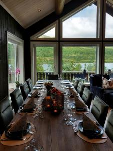 a dining room with a long table with wine glasses at Modern Mountain Cabin With A View Over The Sea in Vevle