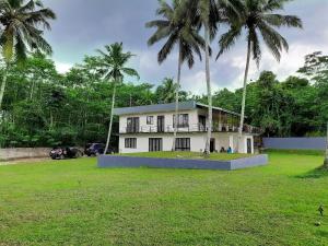 une maison avec des palmiers dans un parc dans l'établissement Golden Riverside Resort Kosgama, à Kosgama