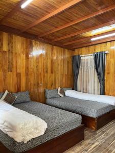 zwei Betten in einem Zimmer mit Holzwänden in der Unterkunft homstay tuấn thơm in Mèo Vạc