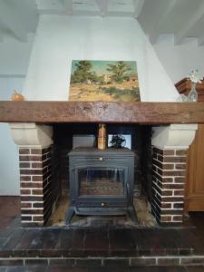 - un salon avec une cheminée et une cuisinière dans l'établissement La Tometterie - longère normande traditionnelle, à Chanteloup