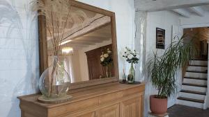 un miroir au-dessus d'une commode en bois avec des fleurs dans l'établissement La Tometterie - longère normande traditionnelle, à Chanteloup 34 autres photos