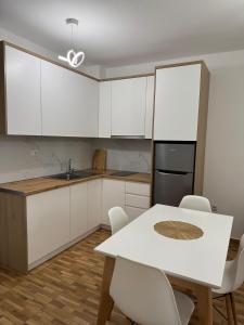 a kitchen with white cabinets and a table and chairs at Apartaments Shengjin with sea view in Shëngjin