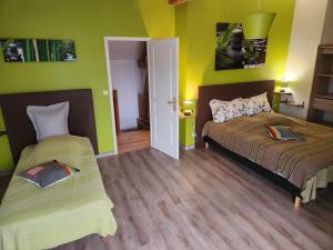 two beds in a room with green walls at Le prieuré in Raslay