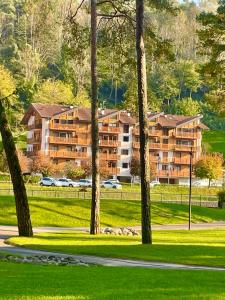 un gran edificio de apartamentos con coches aparcados en un parque en Terrazza sul Parco, en Comano Terme
