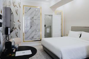 ein weißes Schlafzimmer mit einem Bett und einem Tisch in der Unterkunft Bon Hotel Bishkek in Bischkek