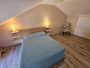 a bedroom with a bed and a chair in it at Gîte du séchoir in Bouresse