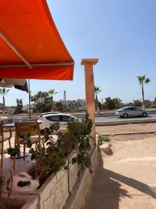 Un patio con una sombrilla naranja y algunos coches. en Appartement Moderne Tamraght plage, en Tamraght Ouzdar