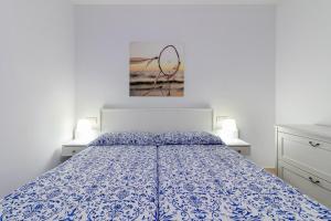 Un dormitorio con una cama con una colcha azul y blanca. en Arinaga Playa 2, en Agüimes