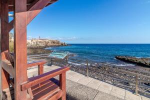 un banco de madera sentado junto al océano en Arinaga Playa 2, en Agüimes