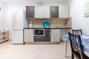 Una cocina con frigorífico, fregadero y mesa. en Arinaga Playa 3, en Agüimes