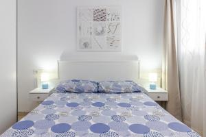 Un dormitorio con una cama azul y blanca con dos lámparas. en Arinaga Playa 3, en Agüimes