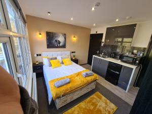 a bedroom with a bed with yellow pillows and a kitchen at YPS Studio Rooms in Peterborough