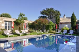 a pool with chairs and a table next to a house at Le Général d'Elbée Hotel & Spa - Teritoria in Noirmoutier-en-l'lle