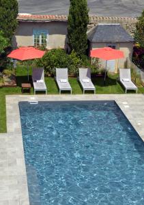 a swimming pool with chairs and umbrellas in a yard at Le Général d'Elbée Hotel & Spa - Teritoria in Noirmoutier-en-l'lle