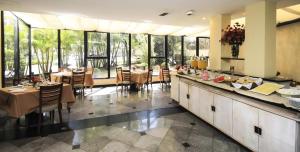 a restaurant with tables and chairs and large windows at Hotel Bienal Ibirapuera Un409 in Sao Paulo