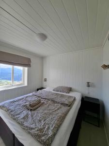a large bed in a white room with a window at Apartment Tråstølen ski in ski out in Vossevangen