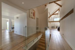 Una puerta pivotante de cristal en un salón con suelo de madera. en Villa Panoramiqua - Vue 180 sur le Lac d'Annecy et les montagnes, en Saint-Jorioz