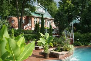 a house with a swimming pool and plants in front of it at La Belle aux Berges in Saint-Denis-sur-Richelieu