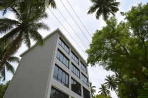 a white building with palm trees in front of it at Mottel AC Room with Breakfast at Calangute in Calangute