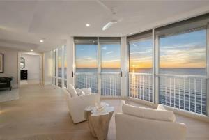 a living room with white chairs and a view of the ocean at Gulf-front Masterpiece in Naples