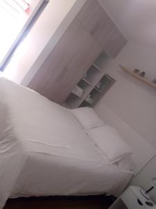 ein Schlafzimmer mit einem großen weißen Bett mit weißen Kissen in der Unterkunft Cómodo monoambiente en El Prado in Cochabamba