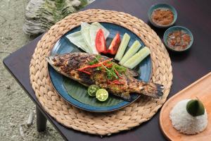 a plate of food with fish and vegetables on a table at Batumera in Pulau Payung Besar