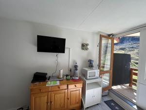 a kitchen with a microwave and a tv on the wall at Studio Les Cimes au pied des pistes in La Mongie