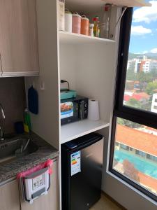 eine Küche mit einem schwarzen Kühlschrank neben einem Fenster in der Unterkunft Cómodo monoambiente en El Prado in Cochabamba