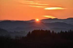 a sunset over a mountain range with trees in the foreground at Ca' le Stelle in Valmaggiore