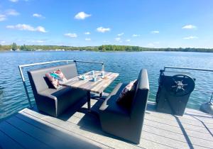 a wooden dock with a table and chairs on a boat at Houseboat Marina Mookerplas 4-6 persons with Hottub in Middelaar +24 photos