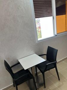 a table and two chairs in a room with a window at Studio Riviera in Tangier